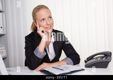 A young, successful businesswoman sits at her desk in the office, Eine junge, erfolgreiche Geschaeftsfrau sitzt an ihrem Schreib Stock Photo