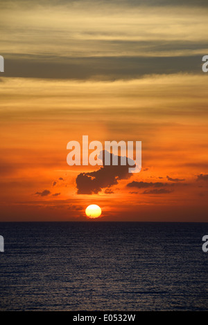 Orange ball sunset near horizon with clouds and sun rays over the Atlantic Ocean in Varadero Cuba Stock Photo