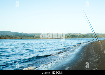 Fishing poles standing in sand waiting for fish to bite, on edge of Ohope Harbor, Bay of Plenty, New Zealand. Stock Photo