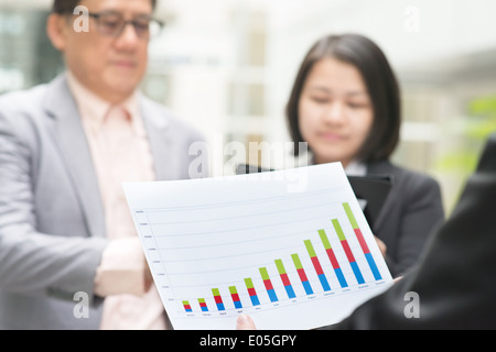 Asian business team meeting. Young business executive presenting charts to CEO boss over office. Stock Photo