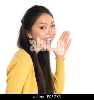 Asian woman holding hand beside her cheek and shouts an announcement, isolated on white background Stock Photo