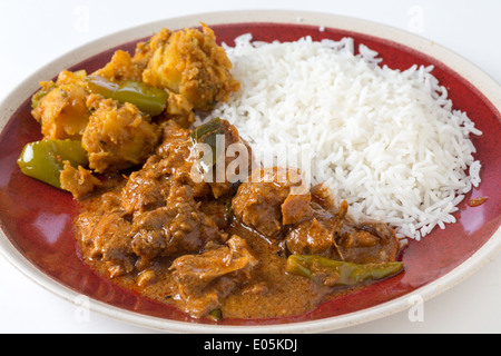 Chettinadu traditional Indian chicken bone-in curry, served with white rice and an aloo capsicum potato and bell pepper dish. Stock Photo