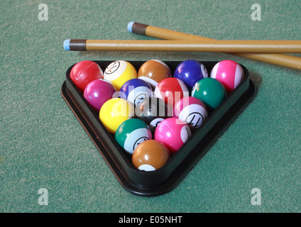 Pool balls on green cloth in triangle with cues Stock Photo