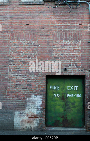 A fire exit doorway in a brick building leading to an alleyway. Stock Photo