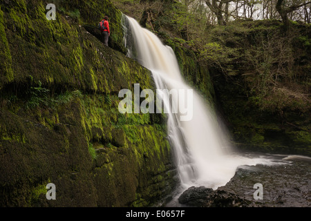 Person stands near Sgwd Clun-Gwyn Waterfall - Afon Mellte river, near Ystradfellte, Brecon Beacons national park, Wales Stock Photo