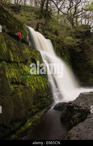 Person stands near Sgwd Clun-Gwyn Waterfall - Afon Mellte river, near Ystradfellte, Brecon Beacons national park, Wales Stock Photo