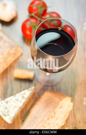 Glass of red wine on top. Bread, tomatoes, cheese nearby. Stock Photo