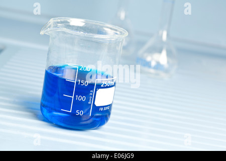 Glass beaker in laboratory filled with blue solutions Stock Photo