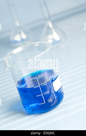 Glass beaker in laboratory filled with blue solutions Stock Photo