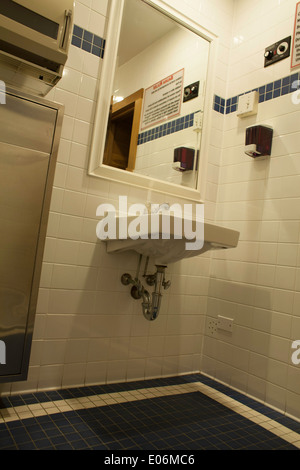 Small tiled public bathroom in a hotel.  Note sauna controls on upper right and in mirror reflection. Stock Photo