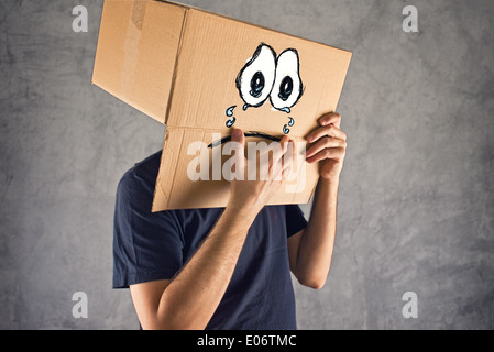 Man with cardboard box on his head and sad crying face expression. Concept of sadness and depression.