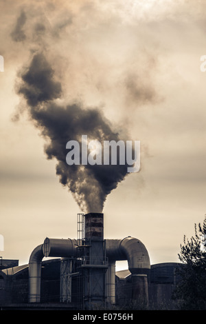 a smokestack erupting toxic fumes in the atmosphere Stock Photo