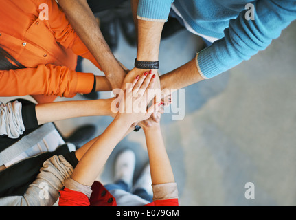 Top view image of group of young people putting their hands together. Friends with stack of hands showing unity. Stock Photo