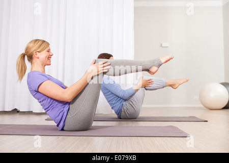 Two fitness women doing pilates exercises lifting their hands at a gym.  Women lying on pilates workout machines while their trainer guides them  Stock Photo - Alamy