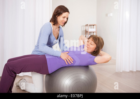 Senior woman on exercise ball receiving physiotherapy