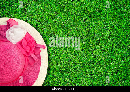 Pink summer hat with silk roses flowers at green texture of garden grass. Image in vintage style Stock Photo