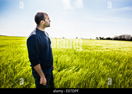 a lone man walking in a big green field Stock Photo