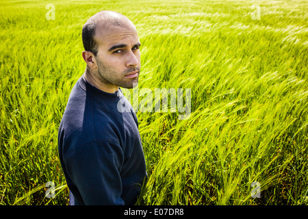 a lone man walking in a big green field Stock Photo
