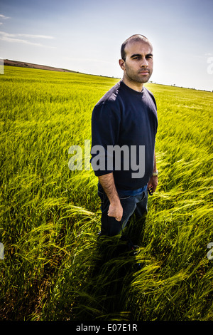 a lone man walking in a big green field Stock Photo