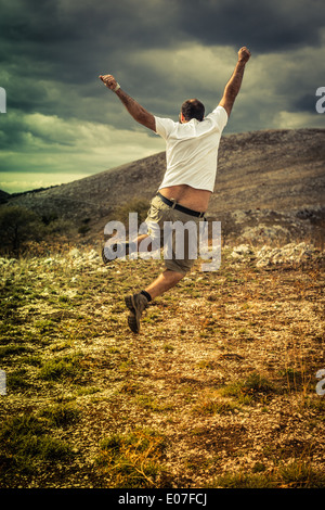 a hiker jumping over a mountainous landscape Stock Photo