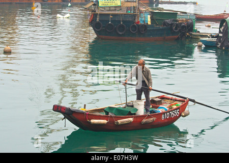 Elderly Chinese Man Rows across the Causeway Bay Typhoon Shelter. Hong Kong. Stock Photo