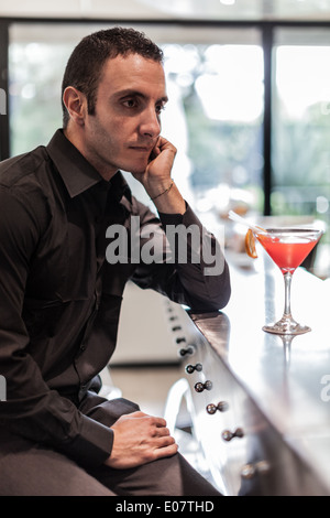 a sad, handsome man sitting at a bar with a pensive attitude Stock Photo