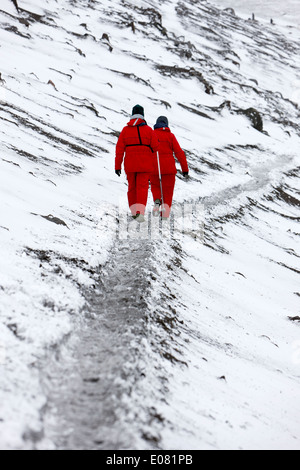 two tourists walking along ridge at hannah point penguin colony Antarctica Stock Photo