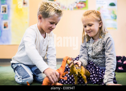 Kids playing with toy dinosaurs in kindergarten Stock Photo