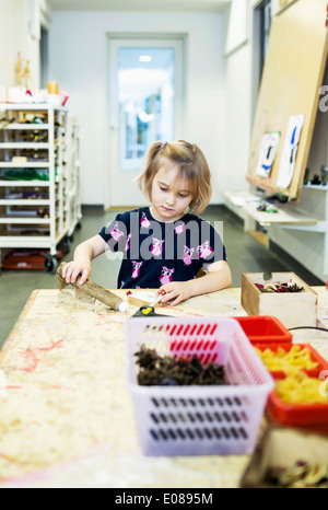 Girl making art product at table in kindergarten Stock Photo