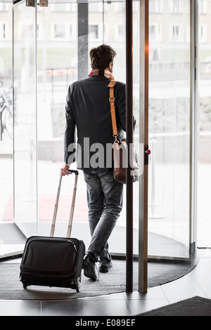 Businessman with luggage leaving hotel Stock Photo