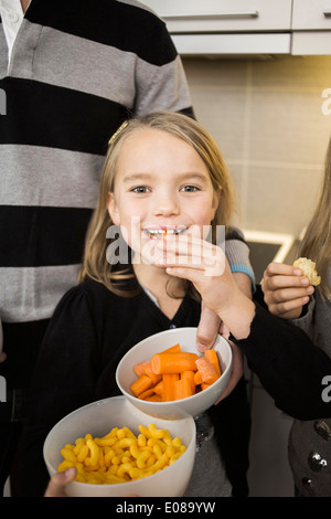 Portrait of little girl eating carrot at home Stock Photo