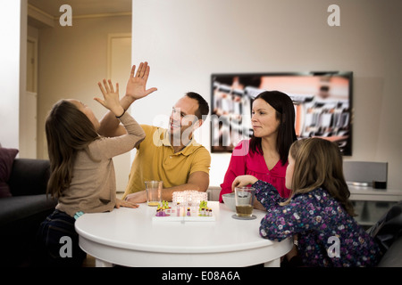 Father and daughter giving high-five while playing ludo at coffee table Stock Photo