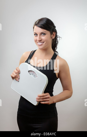 young woman is smiling and holding a weighing scales  Stock Photo