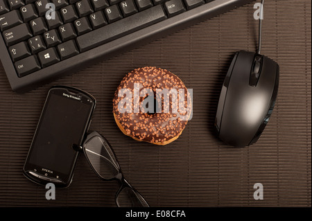 computer keyboard, glasses and cellphone with a doughnut Stock Photo