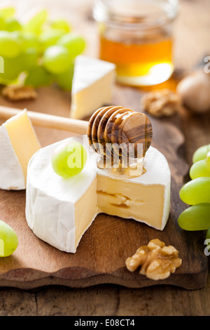 camembert cheese with grapes, honey and nuts on wooden background Stock Photo