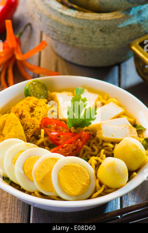 Spicy curry instant noodles. Asian cuisine, ready to serve on wooden dining table setting. Fresh hot with steamed smoke. Stock Photo