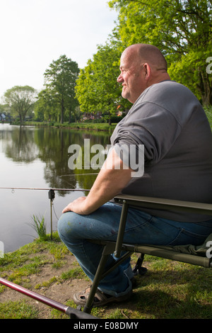 Fisherman sitting near lake with fishing rods Stock Photo