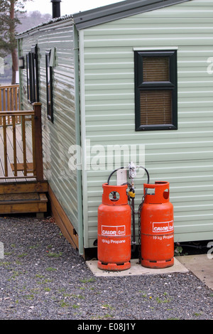 Calor gas red butane / propane bottles next to a static caravan, mobile home in the Lake District Stock Photo