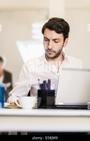 Office Worker With Coffee At Desk Working Late On Laptop Stock Photo ...