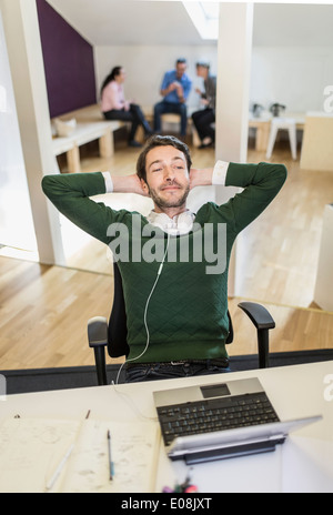 Smiling businessman with hands behind head relaxing in office Stock Photo