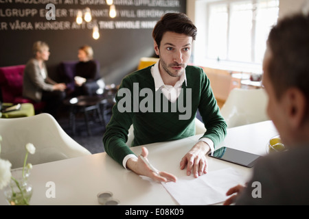 Serious businessman discussing with colleague at office desk Stock Photo