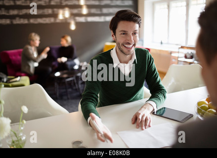 Happy businessman discussing with colleague at office desk Stock Photo