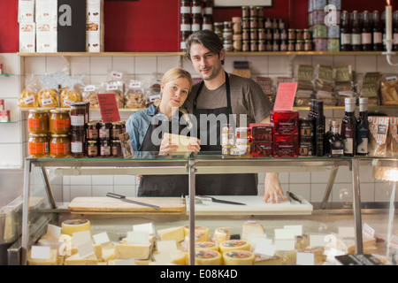 Portrait of male and female worker standing at display cabinet in supermarket Stock Photo