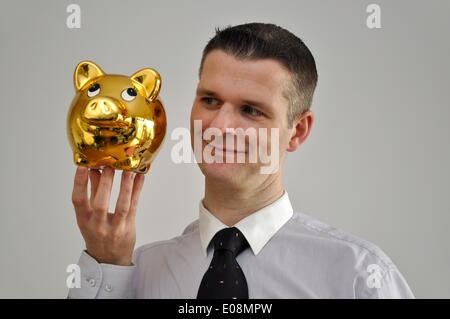 Illustration - A man holds a golden piggy bank in Germany, 27 February 2011. Fotoarchiv für Zeitgeschichte - NO WIRE SERVICE Stock Photo
