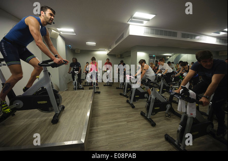 Fitness instructor in front of people riding stationary bicycles during a spinning class at the gym Stock Photo