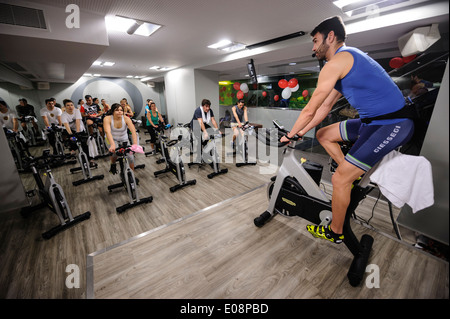 Fitness instructor in front of people riding stationary bicycles during a spinning class at the gym Stock Photo