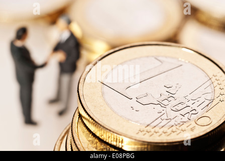 Euro coins and two businessmen in the background Stock Photo