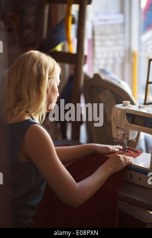 Side view of female fashion designer sewing in studio Stock Photo