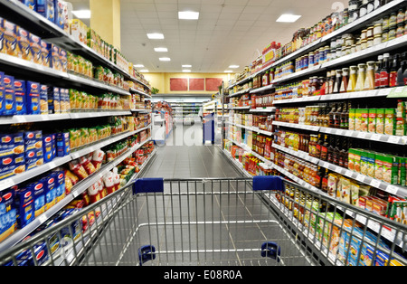An empty cart between shelves in the supermarket. Stock Photo