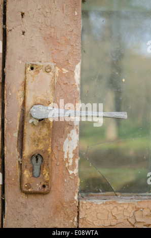 rusty door fragment with old paint scratched door handle with key hole Stock Photo